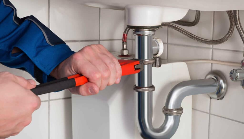 Handyman repairing an water pipe under sink