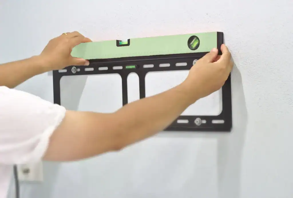 A person is putting a tv on a wall