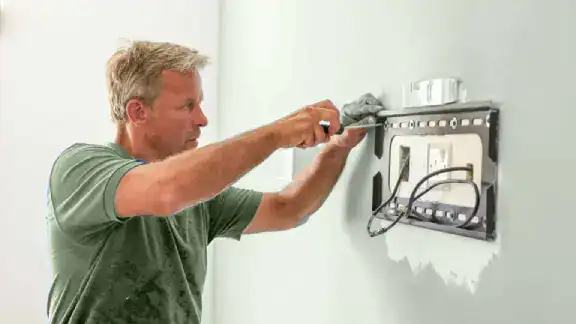 A man is installing a light switch in a room